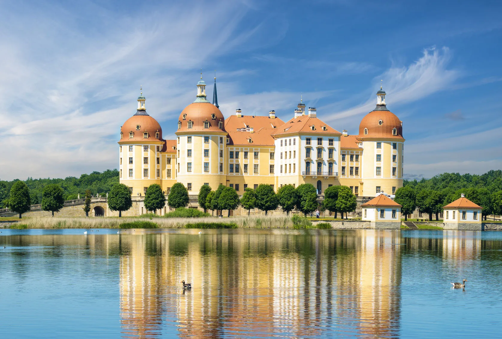Lebensfreunde Dresden - Seniorenbetreuung und Kinderbetreuung - Das ist Schloss Moritzburg, ein Barockschloss in der Nähe von Dresden, Deutschland, bekannt für seine gelbe Fassade und die rotgedeckten Kuppeln.