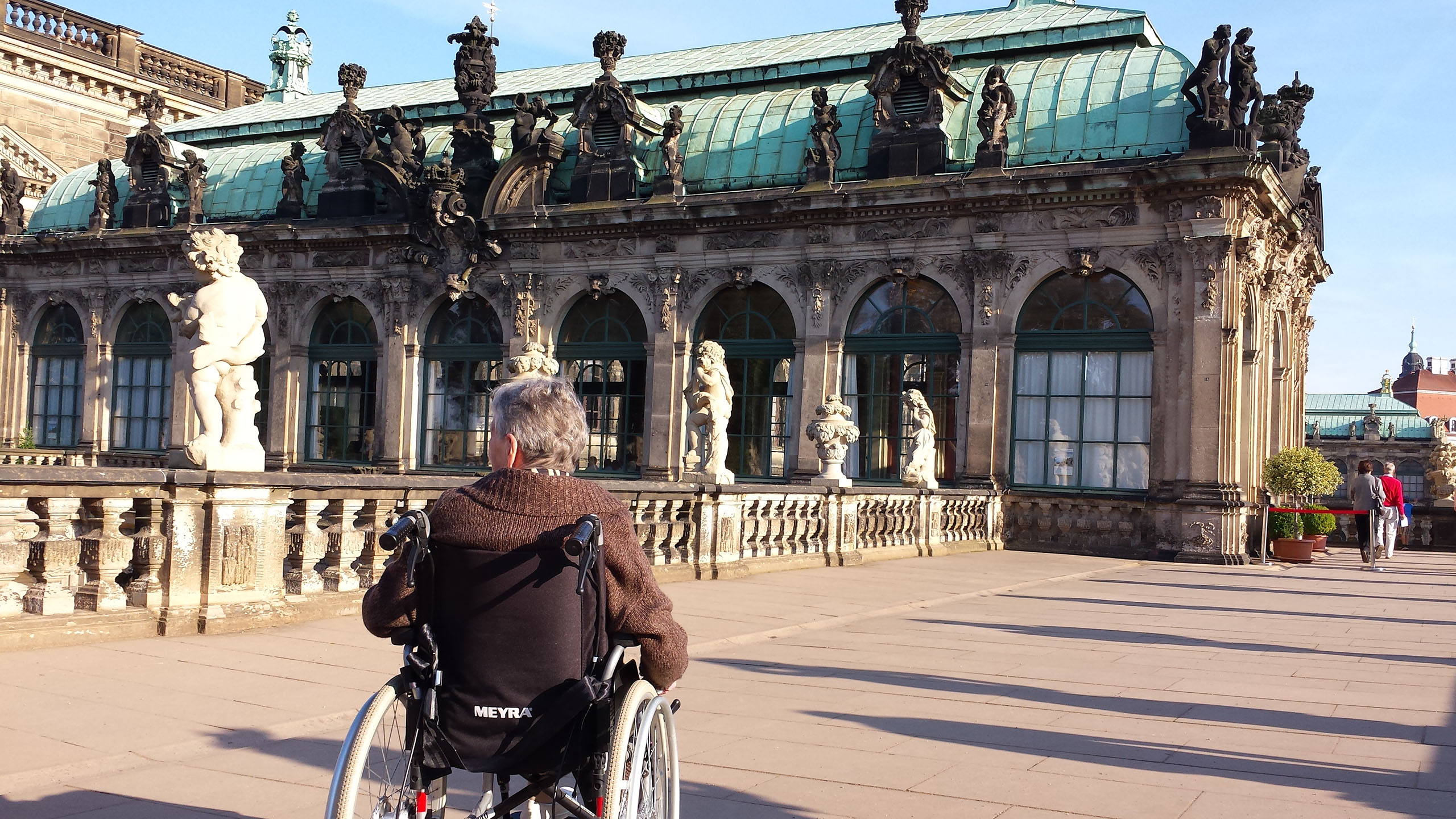 Mann im Rollstuhl vor einem altem Gebäude